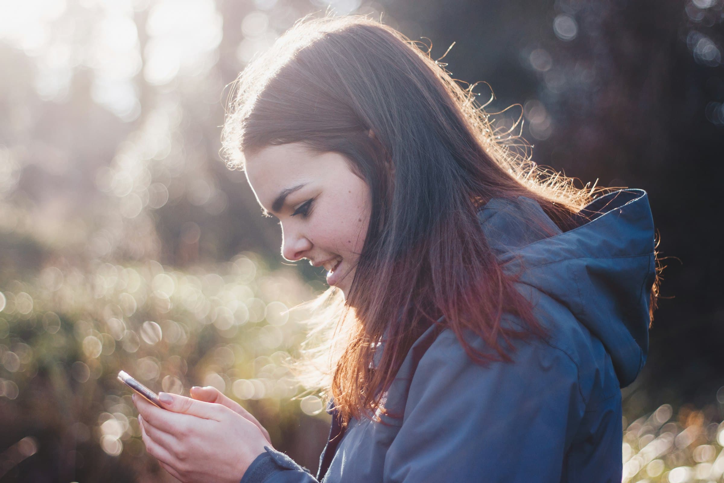 Woman smiling as she reads a message on her phone