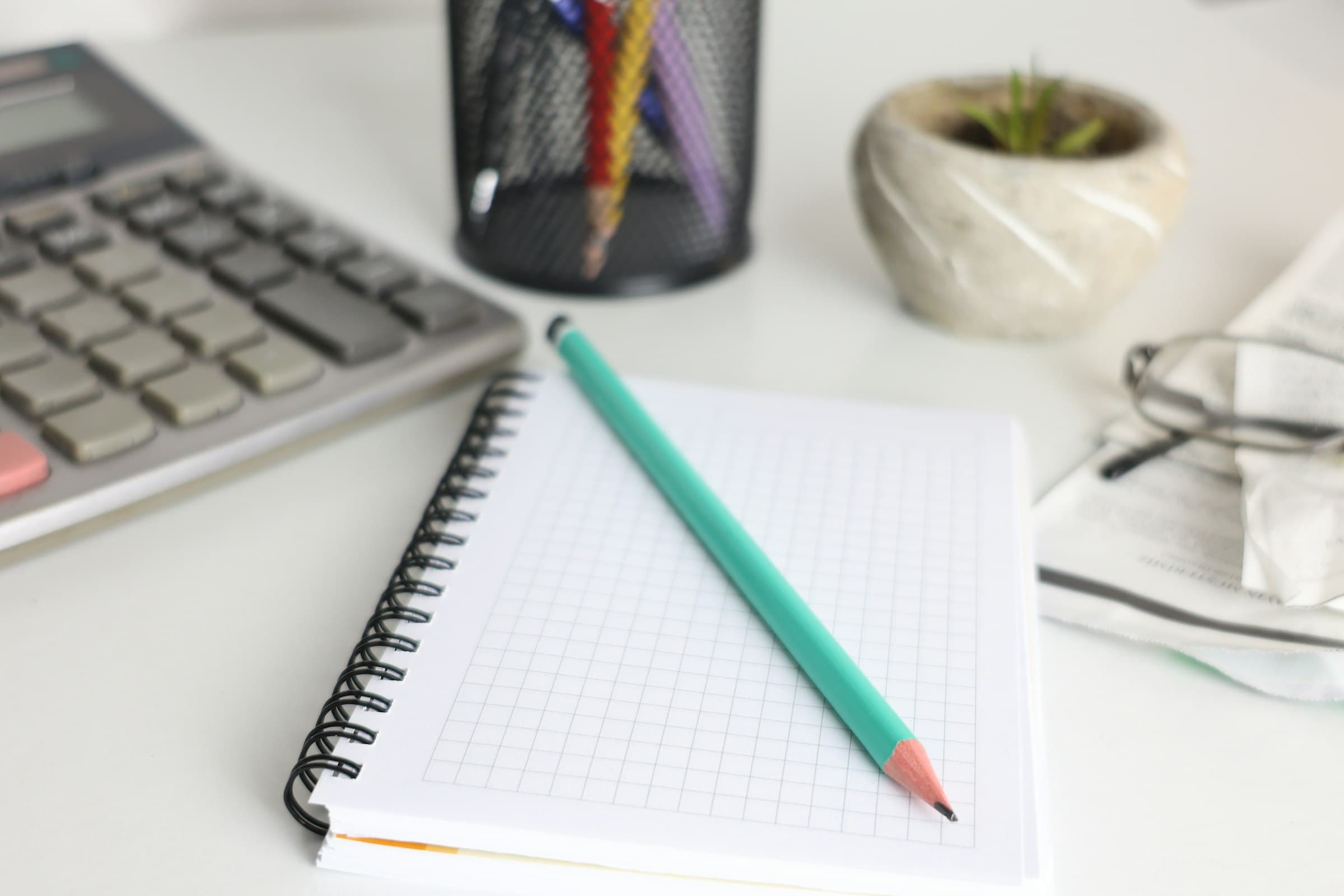 Calculator, notebook, and pencil on a tidy desk